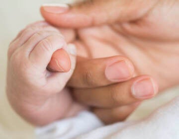 Hispanic mother holding infant's hand