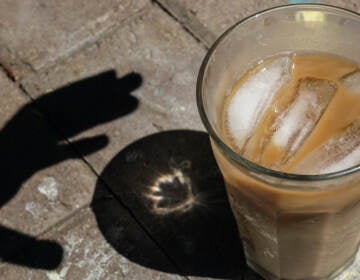 Shadow of a hand reaching for an iced coffee