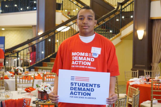 A high school student holds a 'Students Demand Action' sign