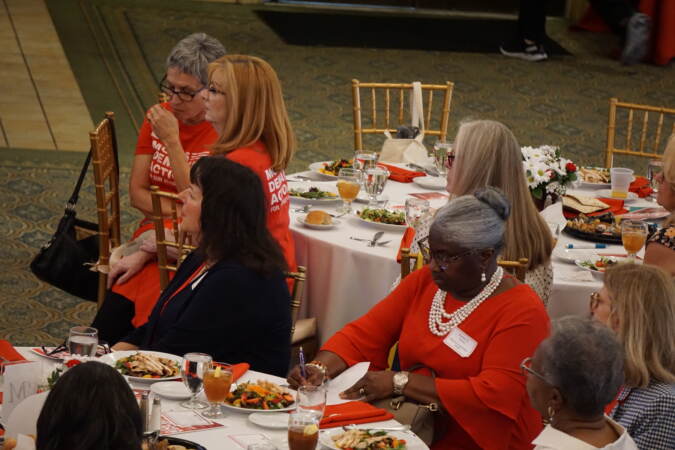 A woman taking notes while a speech is being given at the luncheon.