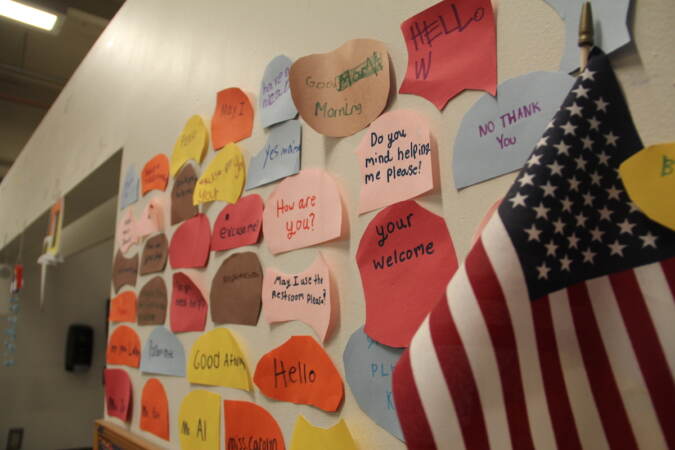 Sticky notes are pasted to a wall. A U.S. flag is visible in the foreground.