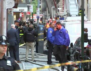 Bystanders and police officers stand near the site of a parking garage collapse.