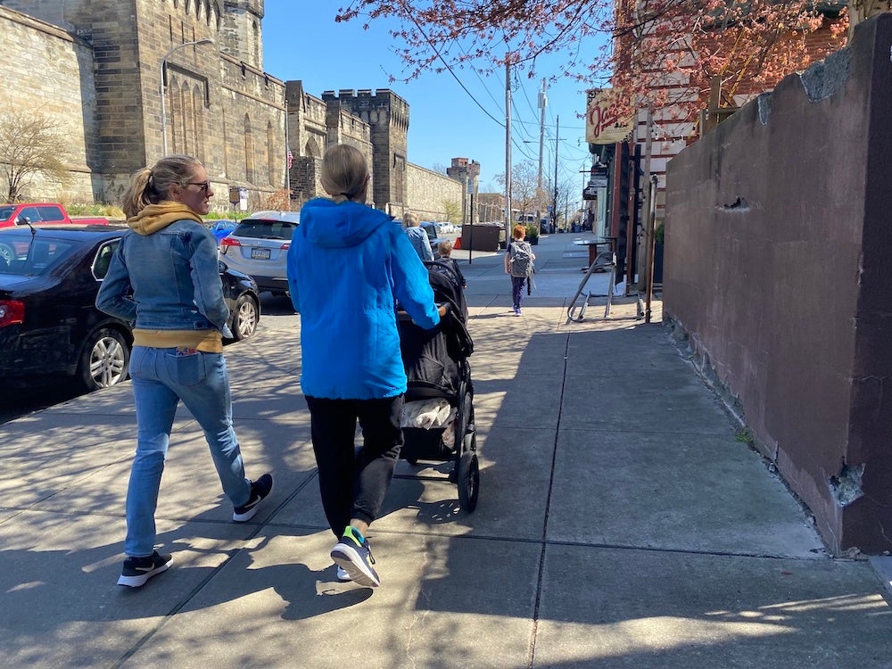 People walk down a street on a sunny day.