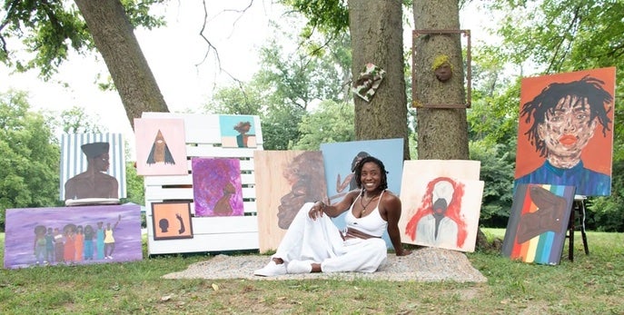 Shari Jones poses with her artwork outdoors.