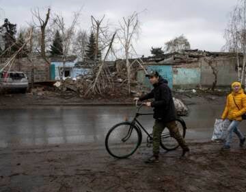 A person rolls a bicycle through the mud in Ukraine.