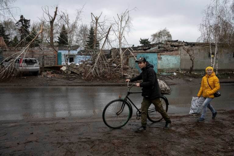 A person rolls a bicycle through the mud in Ukraine.