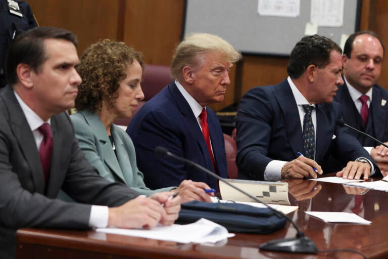 Trump sits at court with his lawyers.