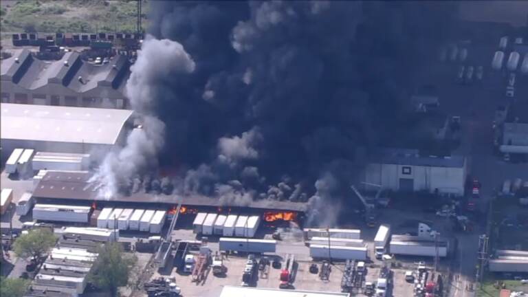 warehouse on fire, with lots of black smoke.