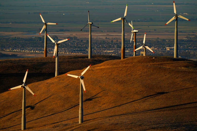 Wind turbines are visible on a hill at sunset.
