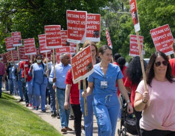 Nurses hold picket signs.