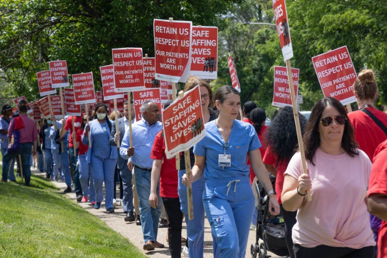 Nurses hold picket signs.