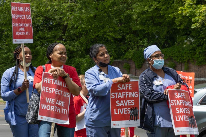 Nurses hold picket signs.