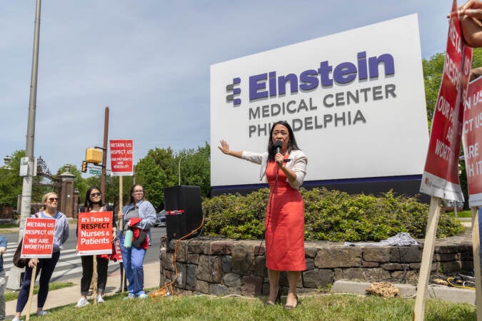 Helen Gym speaks in front of a sign that reads Einstein Medical Center Philadelphia.