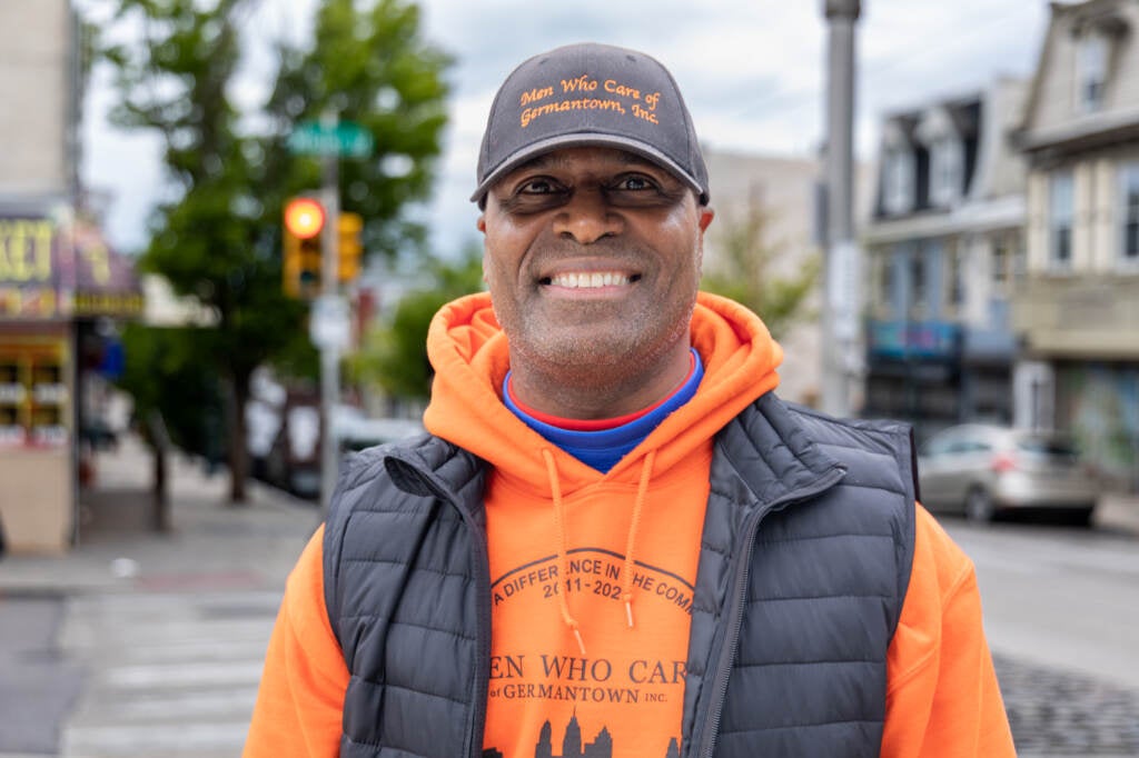 Clayton Justice posing outdoors, with his Men Who Care Germantown hat and sweatshirt