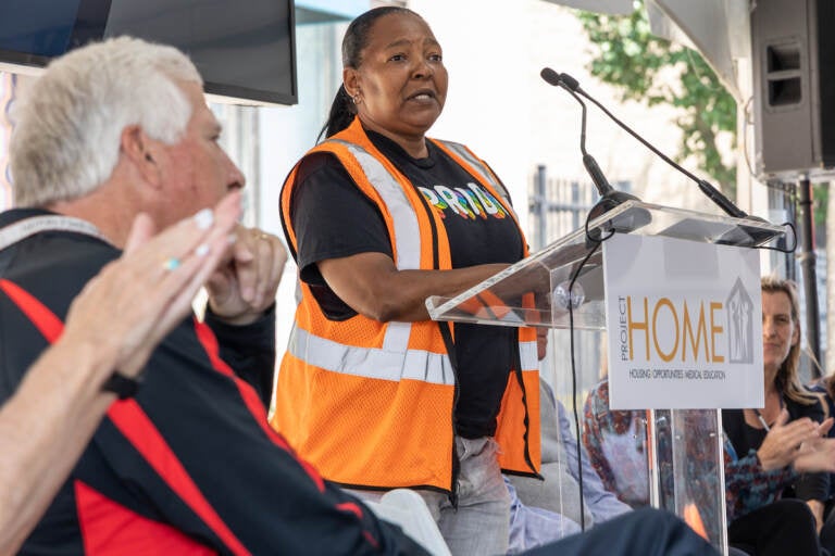 Monique Taylor speaks to an audience while standing at a podium.