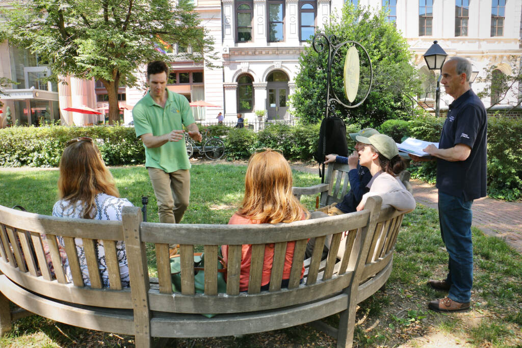 Ken Sandberg performs a story for a group seated on benches in front of him.