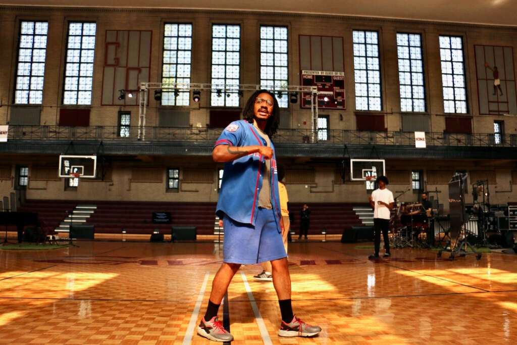 Performer David Gaines walks in the middle of the basketball court/stage.