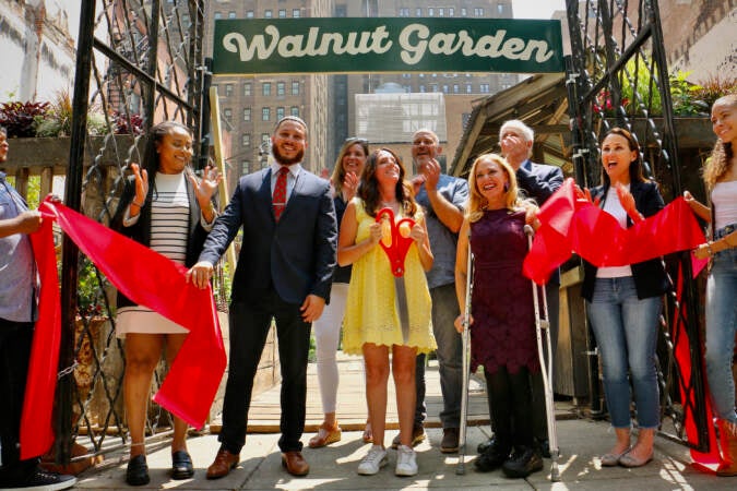 People pose for a photo after a ribbon-cutting ceremony in front of a sign that reads 