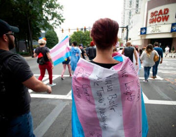 A supporter for the transgender and non-binary community, wearing a transgender flag with handwritten names of black trans women who were killed in 2019 during the Gay Pride Festival's Transgender Rights March in Atlanta on Saturday, Oct. 12, 2019. (AP Photo/Robin Rayne)