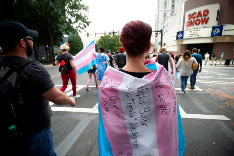 A supporter for the transgender and non-binary community, wearing a transgender flag with handwritten names of black trans women who were killed in 2019 during the Gay Pride Festival's Transgender Rights March in Atlanta on Saturday, Oct. 12, 2019. (AP Photo/Robin Rayne)