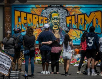 In this May 31, 2020 file photo, visitors make silent visits to organic memorial featuring a mural of George Floyd, near the spot where he died while in police custody, in Minneapolis