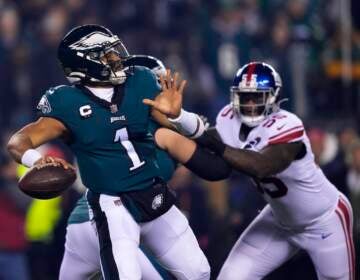 Philadelphia Eagles quarterback Jalen Hurts (1) throws a pass as New York Giants linebacker Jihad Ward (55) tries to rush in on him during the first half of an NFL divisional round playoff football game, Saturday, Jan. 21, 2023, in Philadelphia.