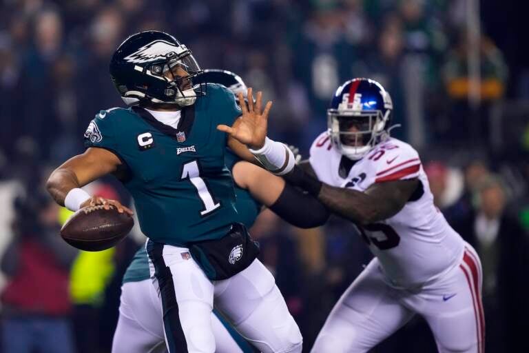Philadelphia Eagles quarterback Jalen Hurts (1) throws a pass as New York Giants linebacker Jihad Ward (55) tries to rush in on him during the first half of an NFL divisional round playoff football game, Saturday, Jan. 21, 2023, in Philadelphia.