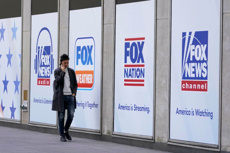 A man walks past the News Corp. and Fox News headquarters on Wednesday, April 19, 2023, in New York. Fox Corp.'s hefty $787.5 million settlement with Dominion over defamation charges is unlikely to make a dent in Fox's operations, analysts say. (AP Photo/Mary Altaffer, File)