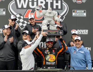 Martin Truex Jr. hoists the trophy after winning the NASCAR 400 auto race at Dover Motor Speedway, Monday