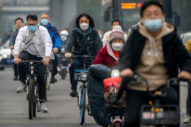 Commuters wearing face masks ride bicycles along a street in the central business district in Beijing, Thursday, Oct. 20, 2022. The World Health Organization downgraded its assessment of the coronavirus pandemic on Friday, May 5, 2023, saying it no longer qualifies as a global emergency. 
(AP Photo/Mark Schiefelbein, File)