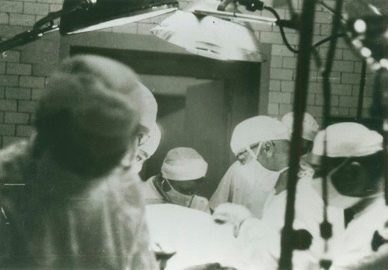 Surgeons at work in a black-and-white photo.