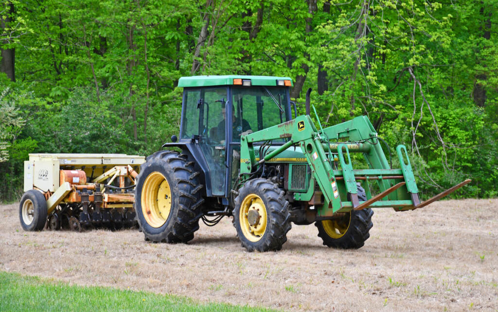 A tractor trailer seeds a patch of ground.