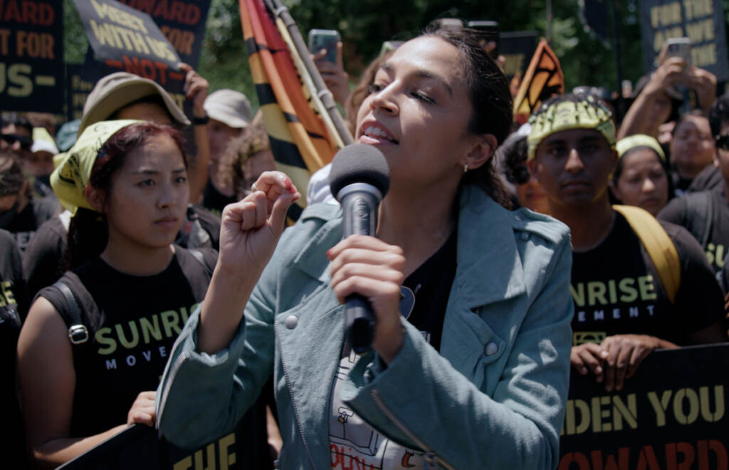 Rep. Ocasio-Cortez speaks into a microphone at a rally for the fight against climate change.