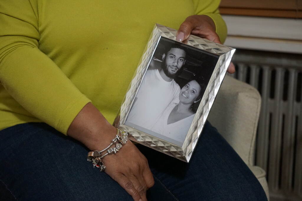 A close-up of Tamika Morales' hands holding a framed photo of her and her son, Ahmad Morales.