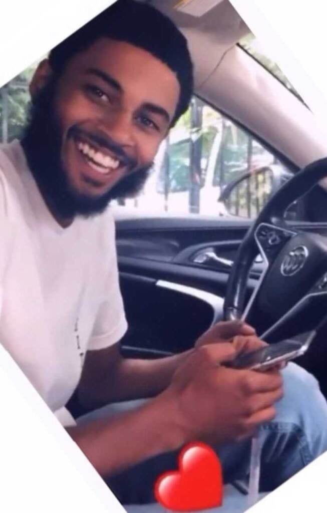 Ahmad Morales smiles as he poses for a photo while seated in a car.