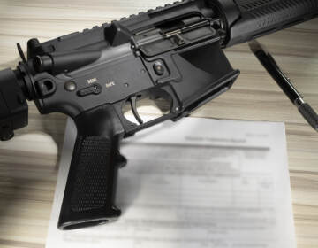 An assault rifle is shown along with paperwork