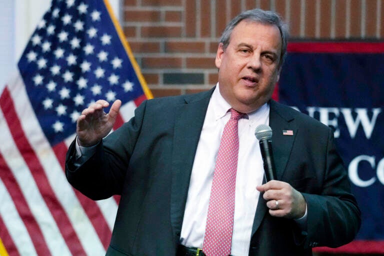 Chris Christie speaks into a microphone. A U.S. flag is visible behind him.