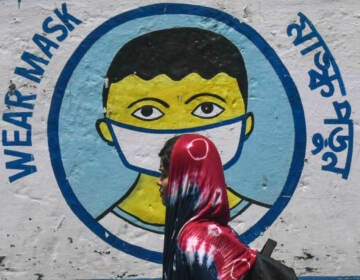 A poster in Kolkata, India, from peak pandemic days sends a message to mask up. Now that the official COVID-19 global emergency is no longer in effect, some folks are thrilled to stop masking — but others wonder if it's a good idea to keep up certain precautions. (NurPhoto via Getty Images)