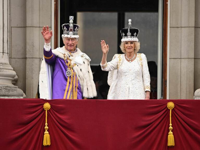 TOPSHOT-BRITAIN-ROYALS-CORONATION Britain's King Charles III wearing the Imperial state Crown, and Britain's Queen Camilla wearing a modified version of Queen Mary's Crown wave from the Buckingham Palace balcony after viewing the Royal Air Force fly-past in central London on Saturday. Oli Scarff/AFP via Getty Images
