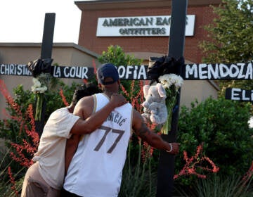 Robert Jackson and his mother Cheryl Jackson hug as they visit a memorial near the scene of a mass shooting at the Allen Premium Outlets mall on Monday in Allen, Texas.