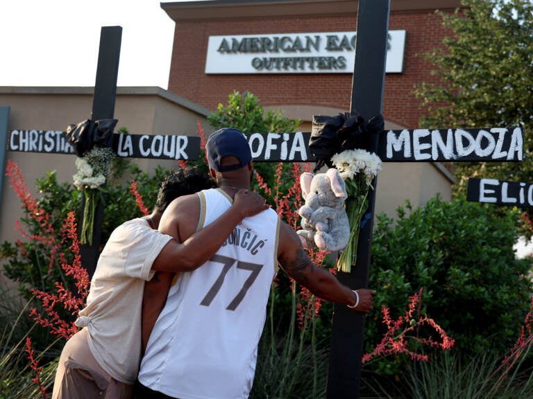 Robert Jackson and his mother Cheryl Jackson hug as they visit a memorial near the scene of a mass shooting at the Allen Premium Outlets mall on Monday in Allen, Texas.