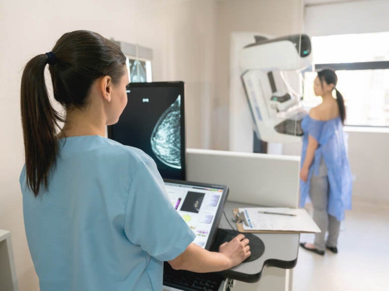 Doctor performing a mammogram on a patient.