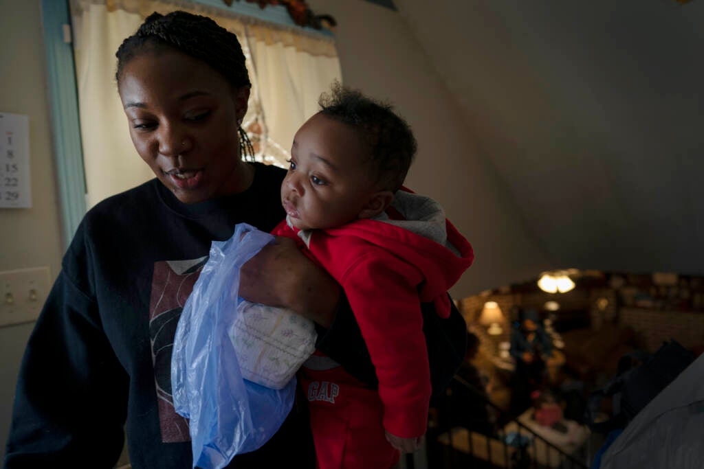 Ansonia Lyons carries her son