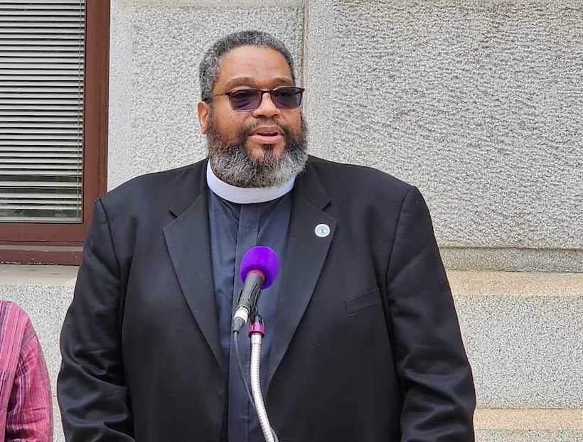 Bishop Dwayne Royster speaks at a podium.