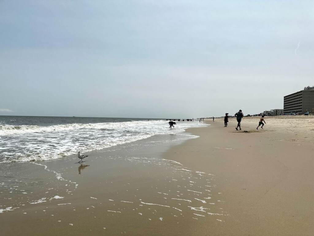 People run on the sand near the waves.