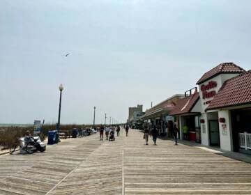 People walk down a boardwalk at Rehoboth Beach on a sunny day.