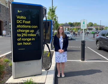 Sarah McBride standing next to an electric vehicle charging station.