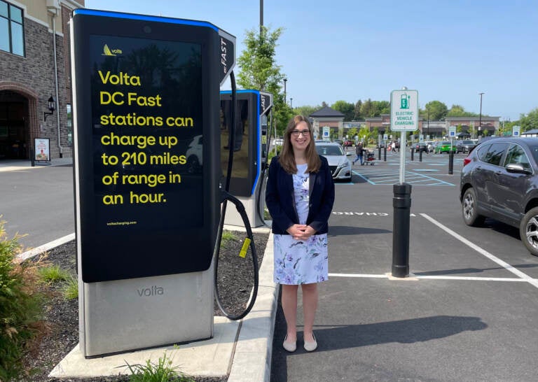 Sarah McBride standing next to an electric vehicle charging station.