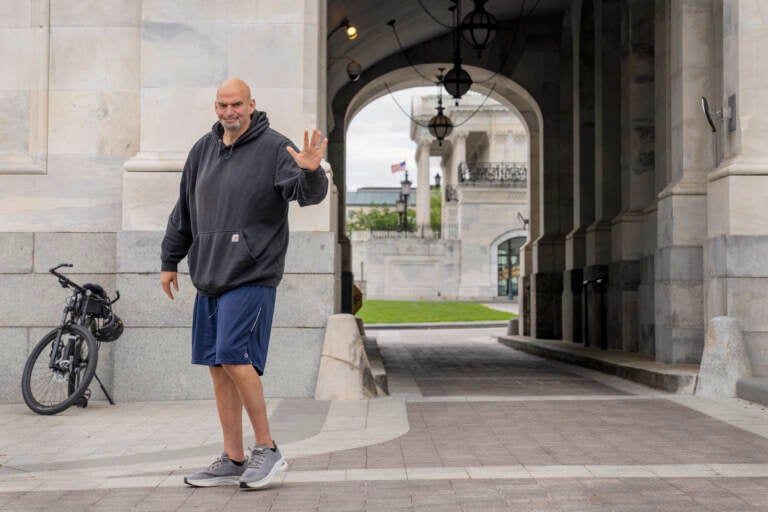 U.S. Sen. John Fetterman waves to the media while wearing gym shorts and a sweatshort