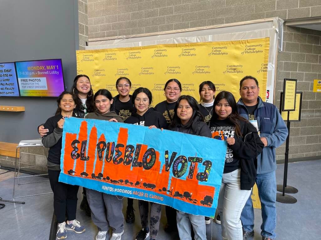 Members of Juntos hold a sign that reads "El Pueblo Vota."